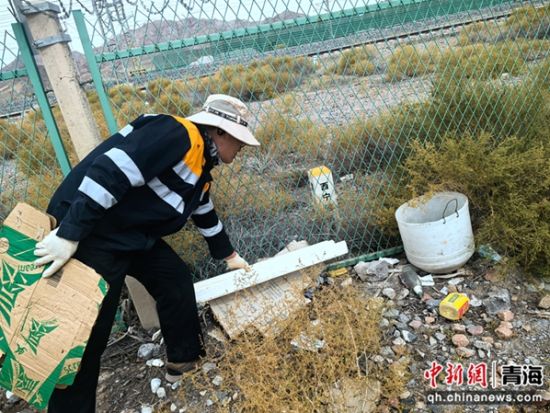 图为职工对铁路网围栏外白色垃圾进行清理。 罗维泰摄 图为职工对铁路网围栏外白色垃圾进行清理。 罗维泰摄