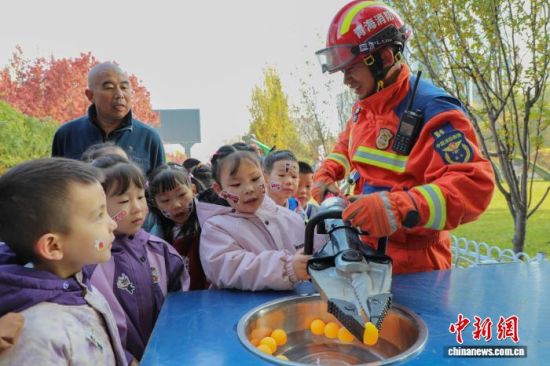 图为消防员协助小朋友体验使用液压剪扩钳夹乒乓球。 马铭言摄 图为消防员协助小朋友体验使用液压剪扩钳夹乒乓球。 马铭言摄