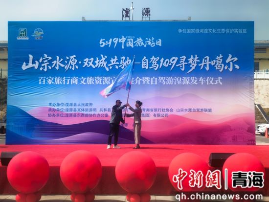 图为湟源县人大副主任杨云霞为自驾车队代表授旗。 祁增蓓摄 图为湟源县人大副主任杨云霞为自驾车队代表授旗。 祁增蓓摄