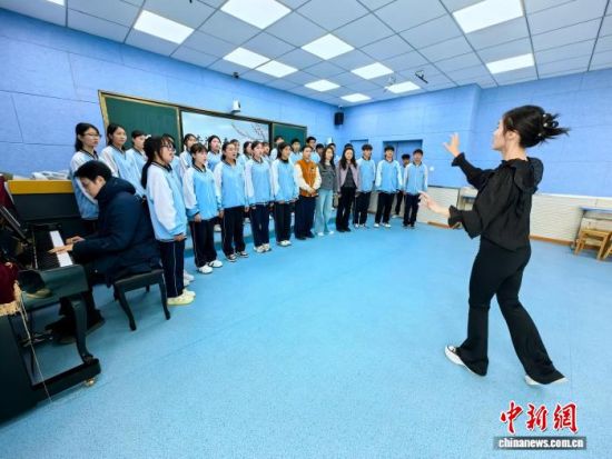 图为聂培欣(右一)和陈昊男(左一)正在指导音乐特色班学生合唱校歌。李隽 摄 图为聂培欣(右一)和陈昊男(左一)正在指导音乐特色班学生合唱校歌。李隽 摄