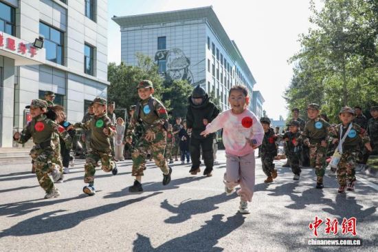 图为“萌娃”正在与着防爆服的人员赛跑。 马铭言摄 图为“萌娃”正在与着防爆服的人员赛跑。 马铭言摄