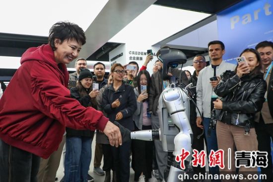 图为吉尔吉斯斯坦嘉宾与机器人握手。马铭言 摄 图为吉尔吉斯斯坦嘉宾与机器人握手。马铭言 摄